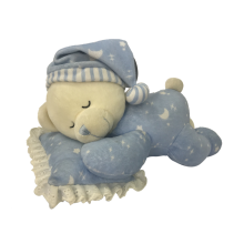 Peluche ours dormant sur des oreillers bleus